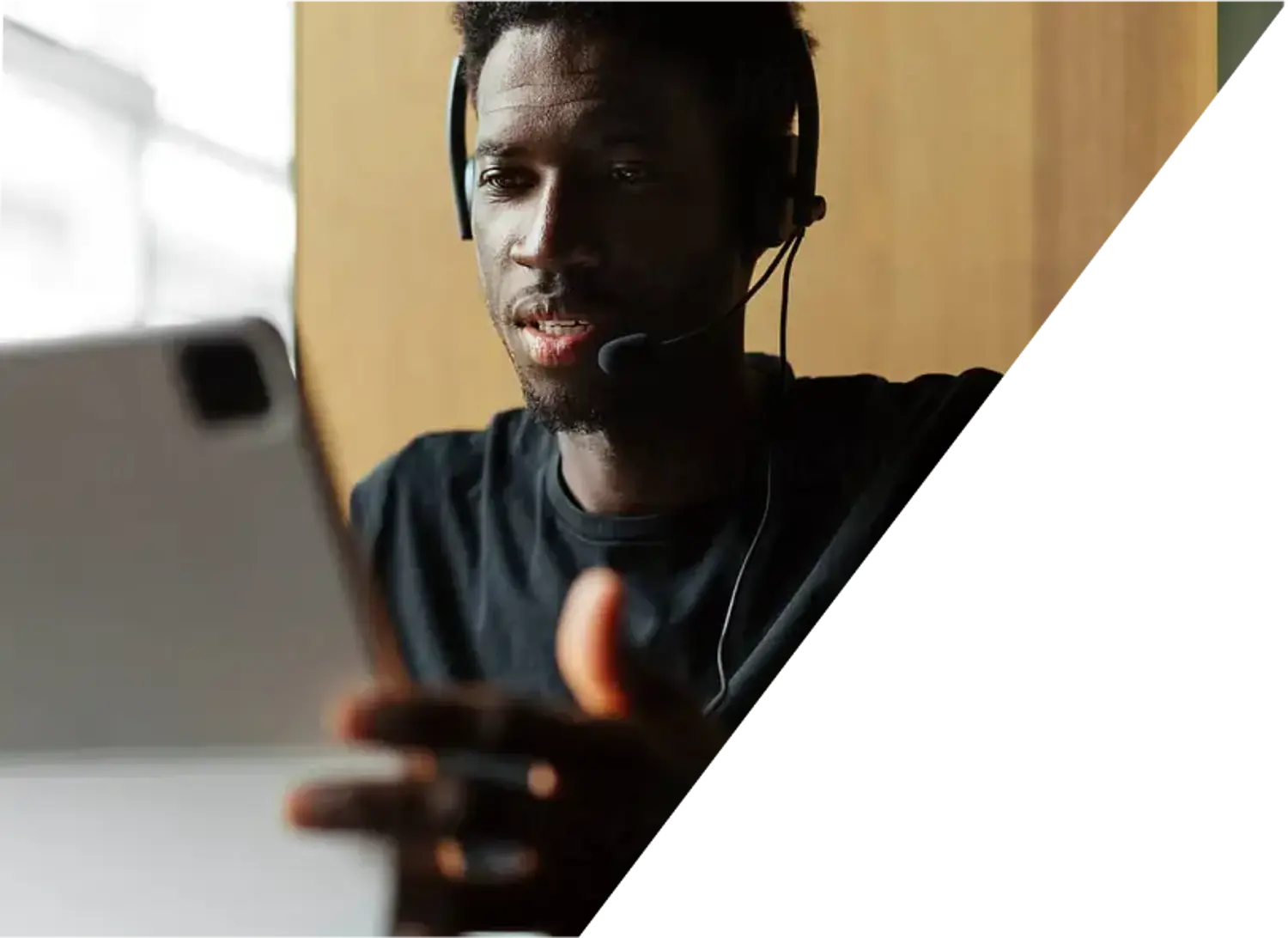 Man with a headset on a phone call with someone while working on his computer.