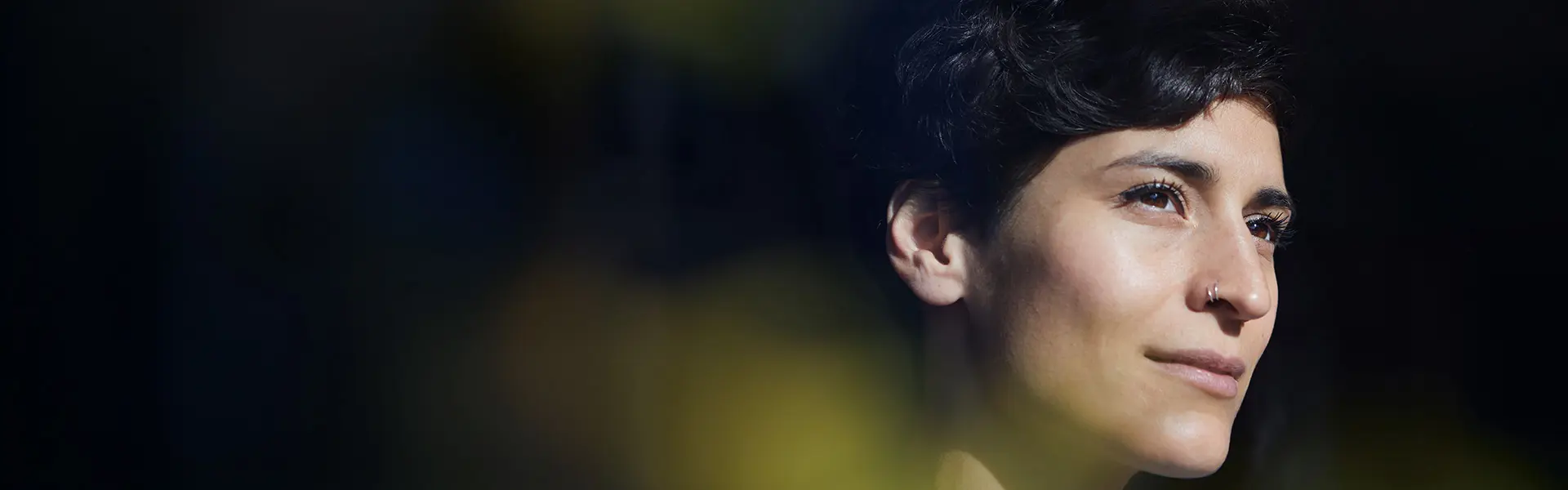 Zoomed in of a woman's face who is looking off into a bright light.